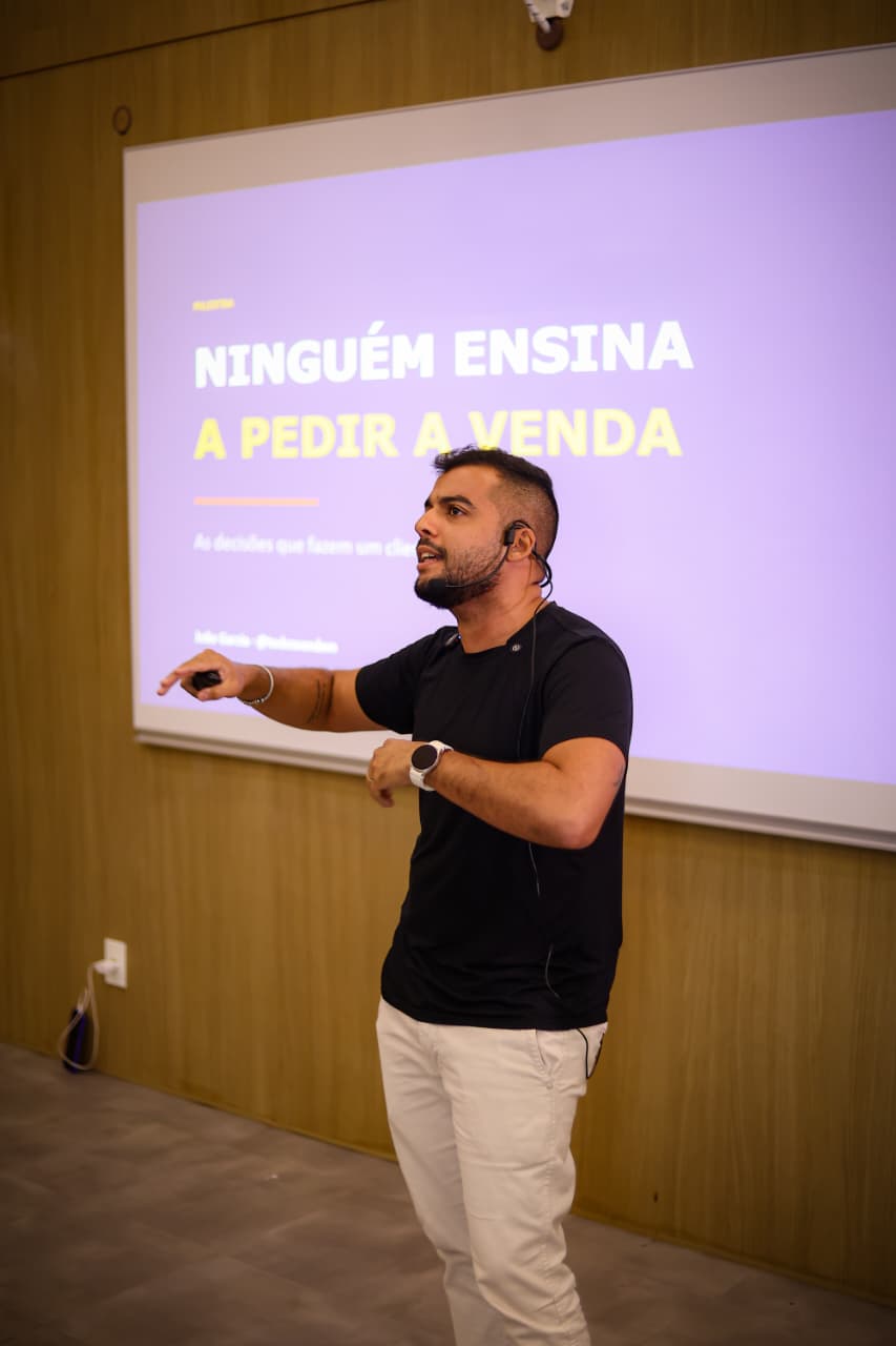 João Garcia palestrando sobre vendas com o slide Ninguém ensina a pedir a venda